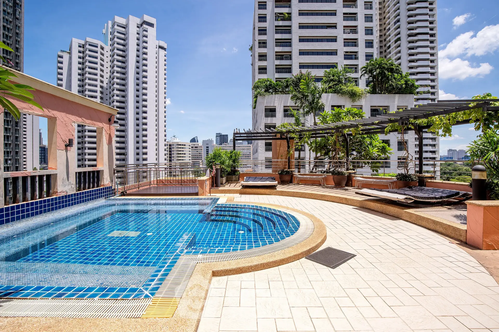Luxurious rooftop pool with stunning city views and lush greenery, perfect for relaxation and entertainment.