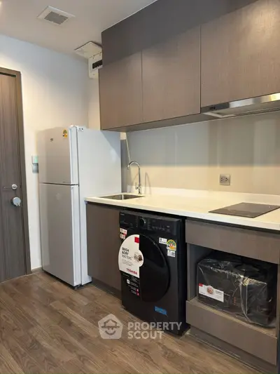 Modern kitchen with sleek appliances and wood flooring in a stylish apartment.