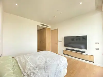 Spacious modern bedroom with wall-mounted TV and elegant wooden flooring