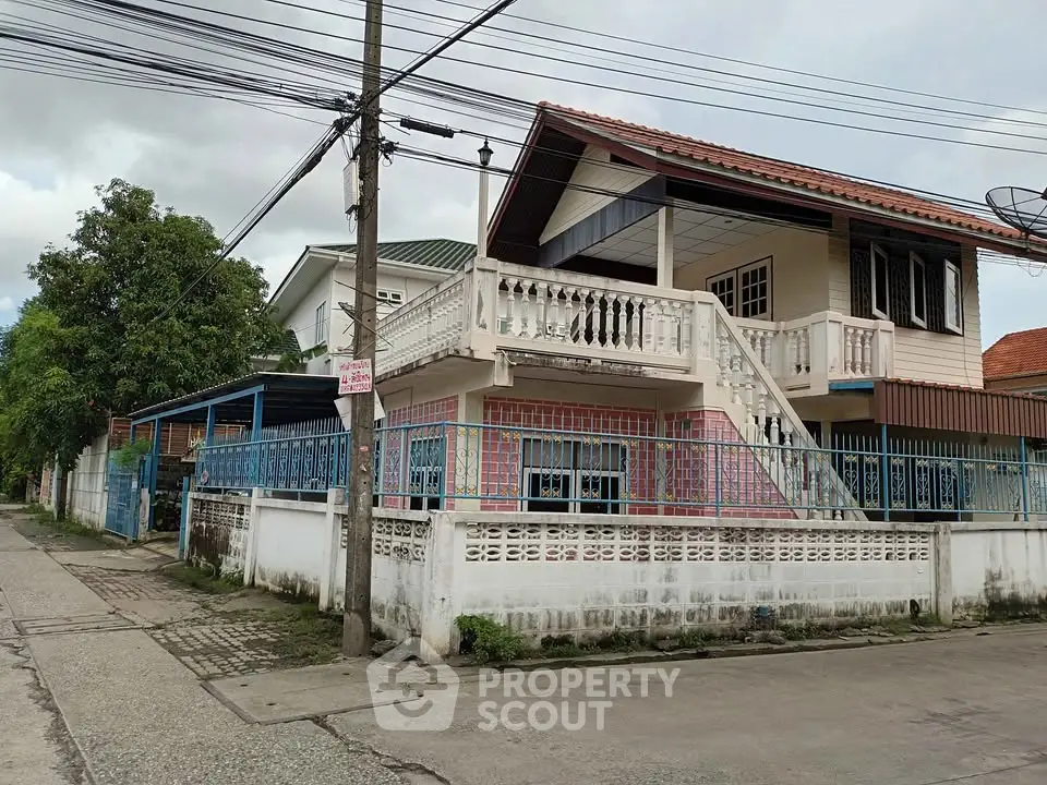 Charming two-story house with balcony and gated entrance in a quiet neighborhood.