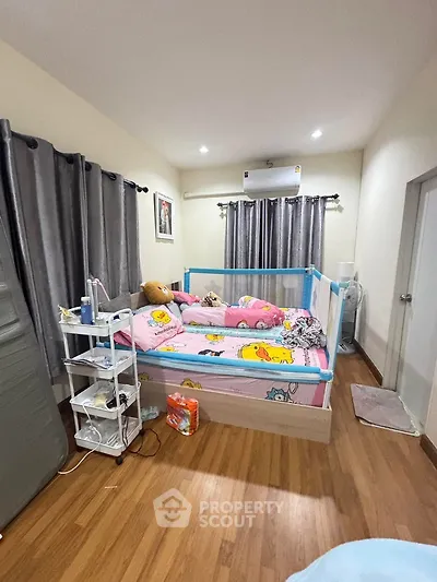 Cozy bedroom with wooden flooring and playful decor, featuring a comfortable bed and ample natural light.