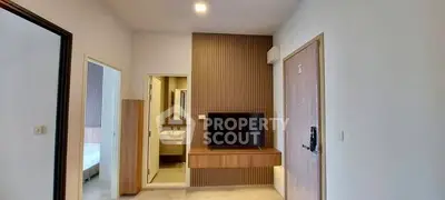 Modern apartment interior with TV and bathroom view, showcasing sleek design and functionality.