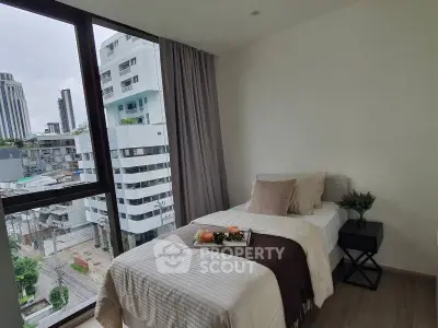 Cozy bedroom with city view, featuring a single bed and modern decor.