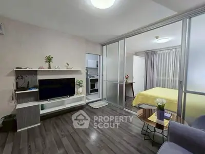 Modern studio apartment with open layout, featuring a cozy living area and bedroom separated by sliding glass doors.