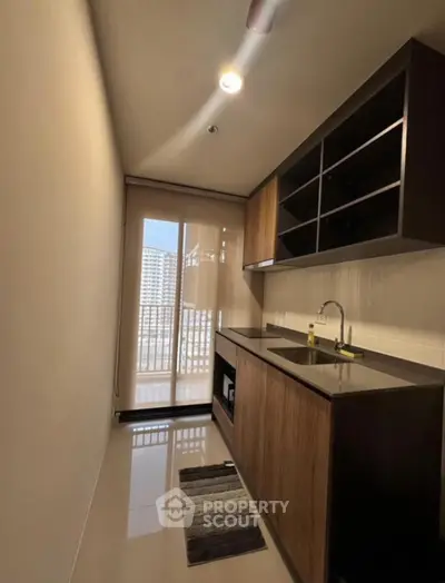 Modern kitchen with sleek cabinetry and balcony view in urban apartment