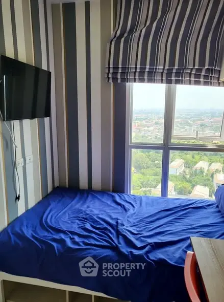 Cozy bedroom with city view, featuring a blue bedspread and wall-mounted TV.