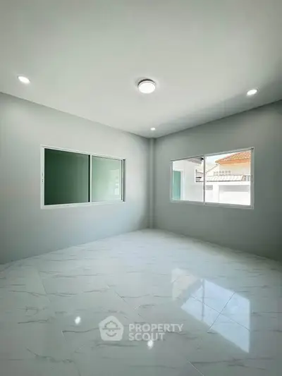Spacious empty room with large windows and modern tile flooring, perfect for customization.