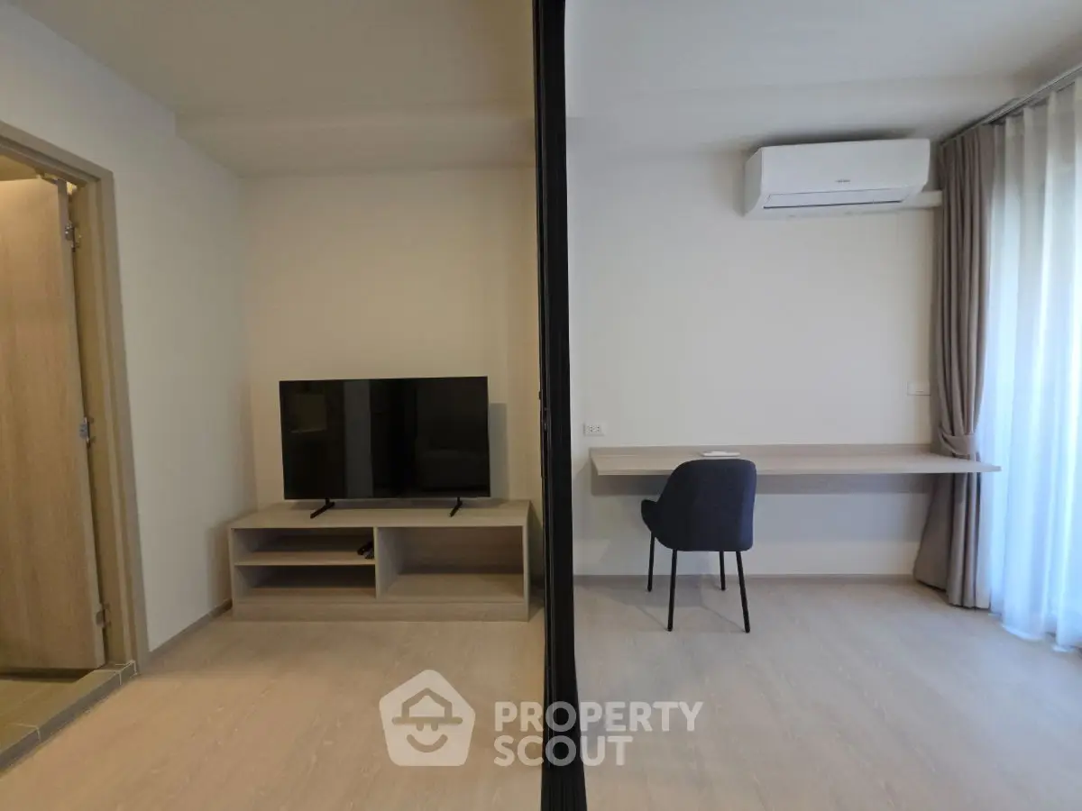 Modern living space with TV and study area, featuring sleek design and natural light.