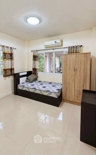 Spacious bedroom with modern furnishings and large windows offering natural light.