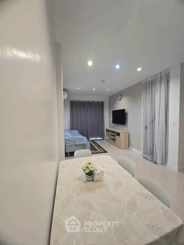 Modern living room with dining area and TV, featuring neutral tones and cozy ambiance.