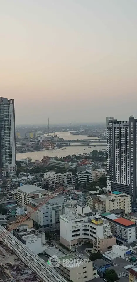 Stunning cityscape view from high-rise building overlooking river and skyline at sunset.