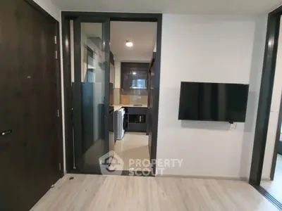 Modern apartment interior with sleek kitchen and wall-mounted TV, showcasing contemporary design.