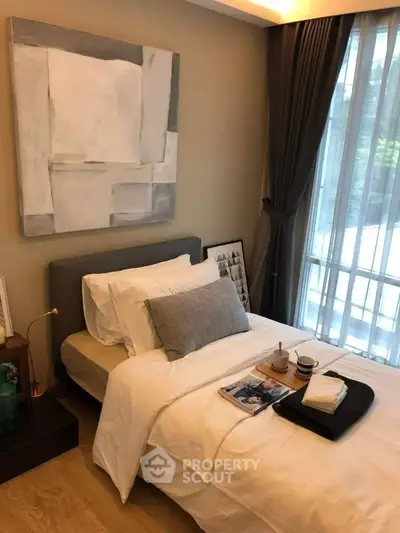 Cozy bedroom with modern decor and large window offering natural light