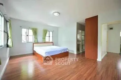 Spacious bedroom with wooden flooring and large windows for natural light