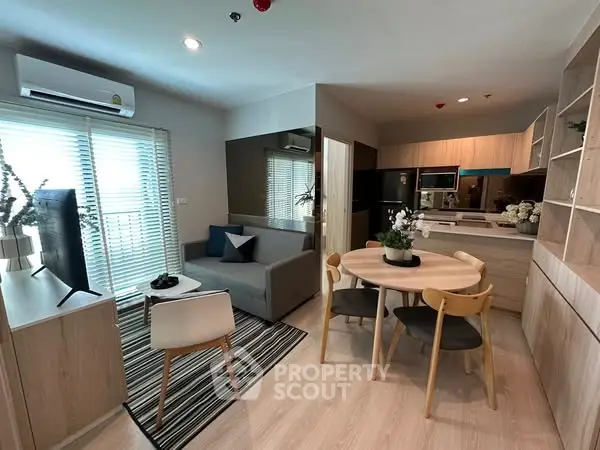 Modern open-layout living room and kitchen with stylish furniture and natural light.