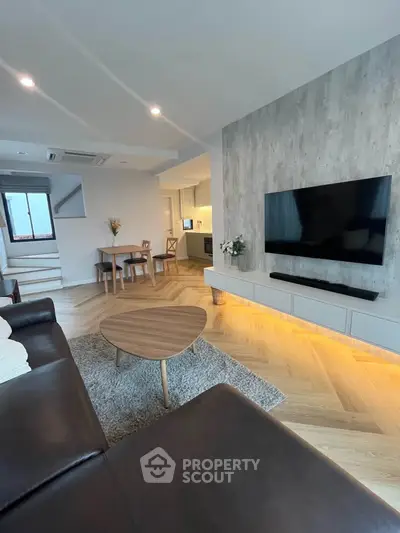 Modern living room with sleek design, featuring a wall-mounted TV and stylish furniture.