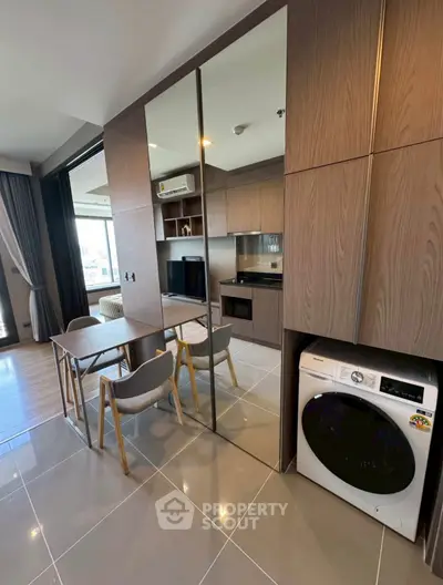 Modern apartment interior with sleek kitchen and built-in washing machine, featuring stylish dining area and large windows.