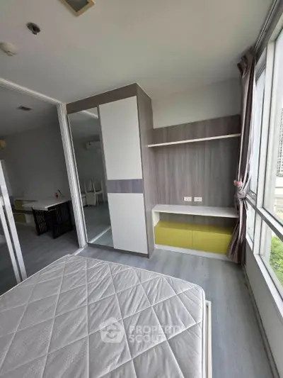 Modern bedroom with large windows and built-in storage in a high-rise apartment.