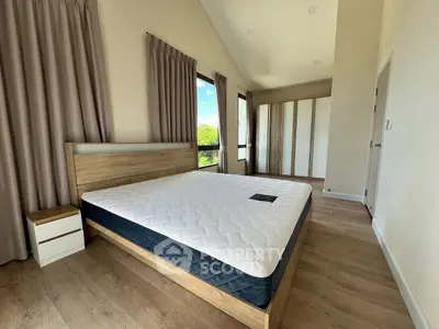 Spacious bedroom with modern wooden furniture and large windows offering natural light.