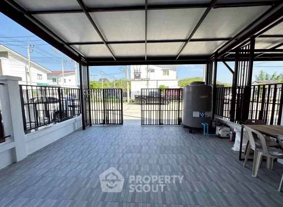 Spacious covered parking area with tiled flooring and metal gate
