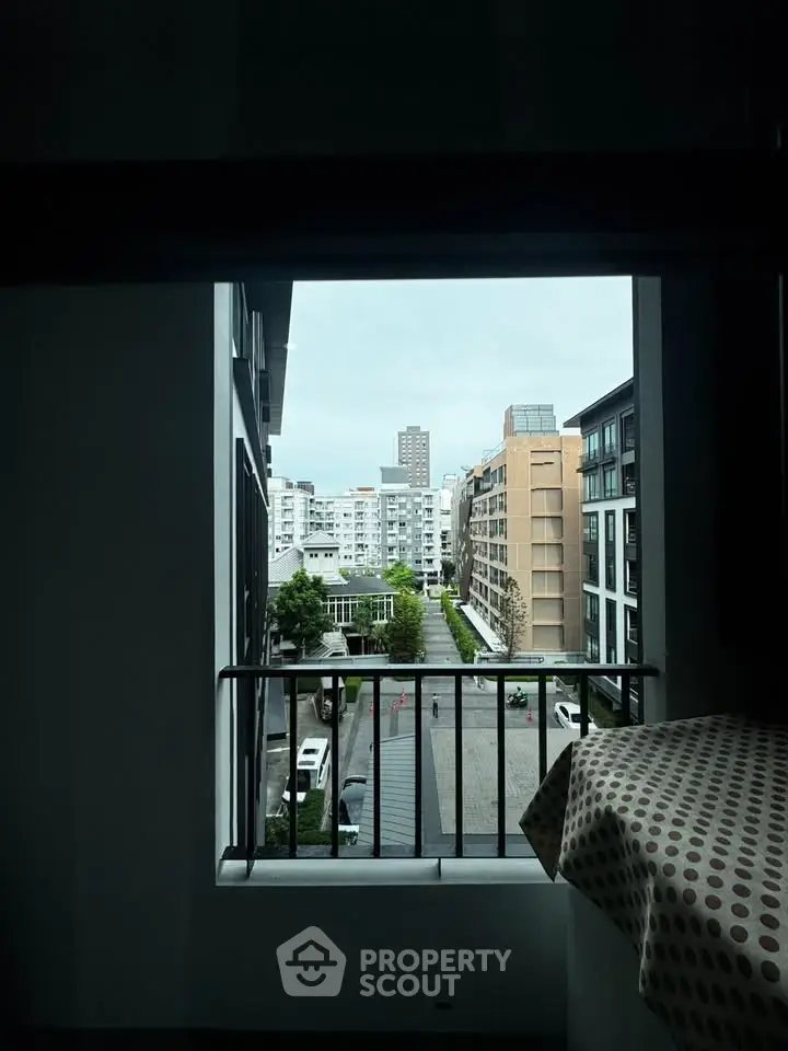 Urban view from a modern apartment window overlooking city buildings and street.