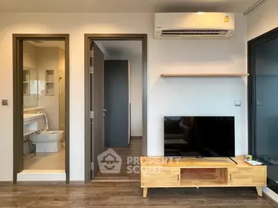 Modern living room with wooden TV stand and air conditioning, adjacent to a sleek bathroom.
