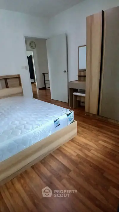 Spacious bedroom with wooden flooring and modern furniture