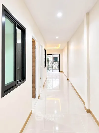 Bright and spacious corridor with modern design and glossy tiled flooring.