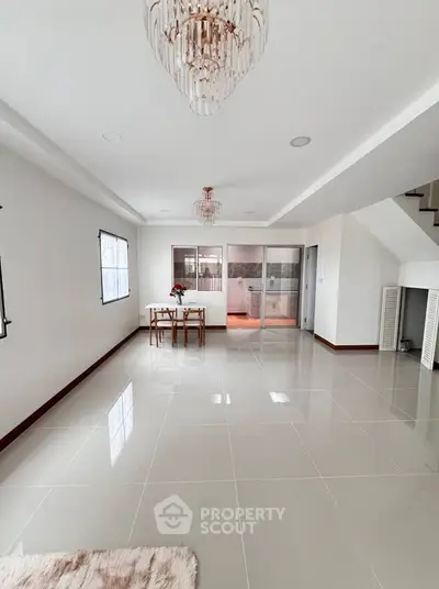 Spacious modern living room with elegant chandelier and open layout, perfect for entertaining.