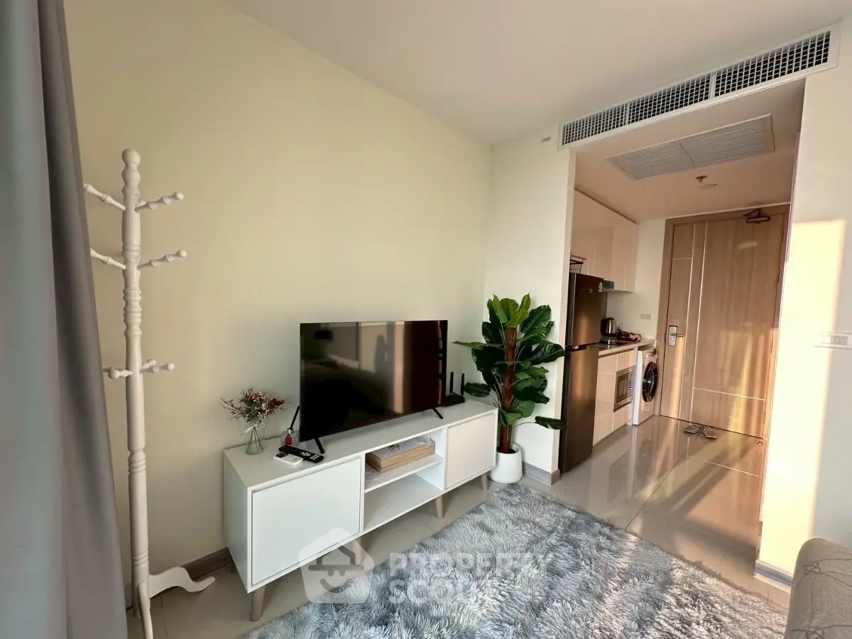 Modern living room with TV, cozy rug, and open kitchen layout in a stylish apartment.