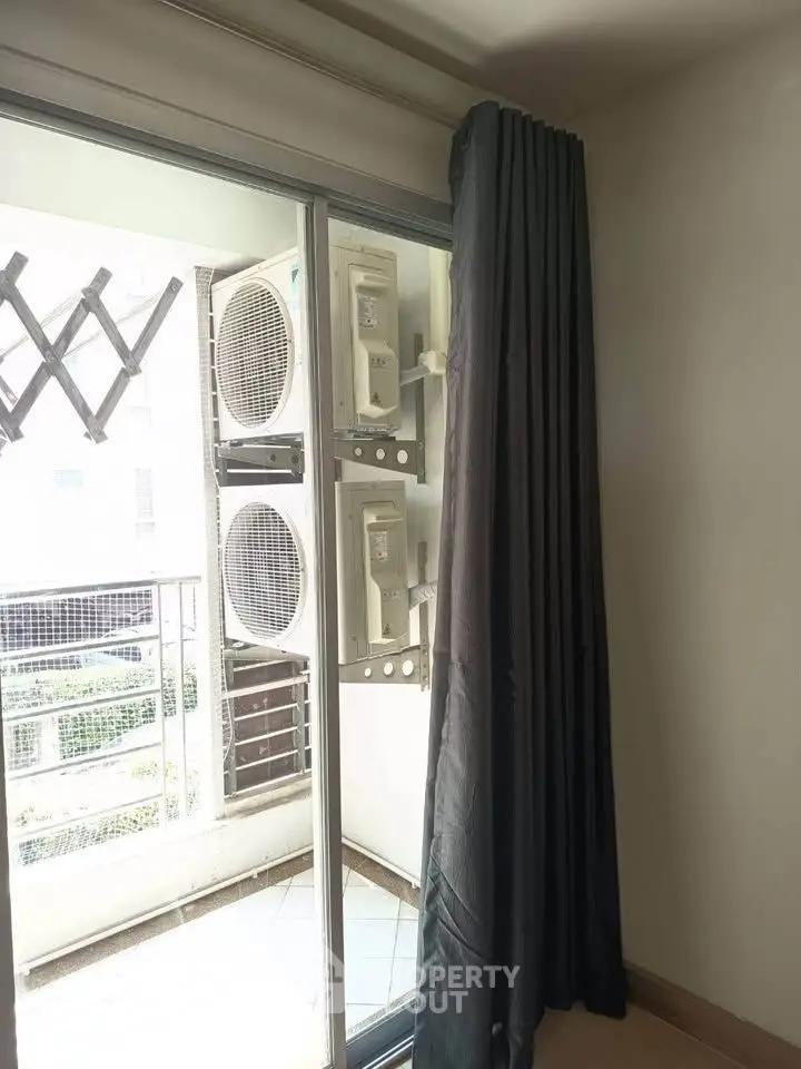 Modern apartment balcony with air conditioning units and sliding glass door.