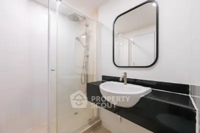 Modern bathroom with sleek shower and stylish sink in contemporary apartment.