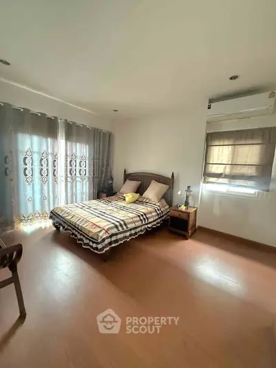 Cozy bedroom with natural light, featuring a stylish bed and elegant curtains, perfect for relaxation.