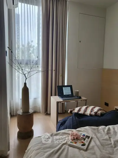 Cozy bedroom with natural light, stylish decor, and a small workspace by the window.