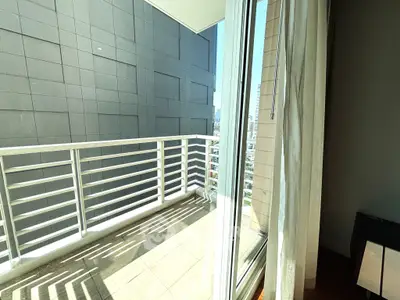 Modern apartment balcony with city view and glass sliding doors, perfect for urban living.
