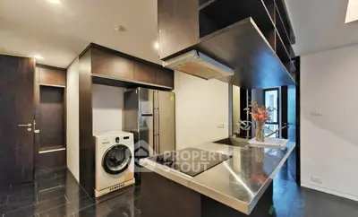 Modern kitchen with sleek appliances and stylish dark wood cabinetry in a contemporary apartment.