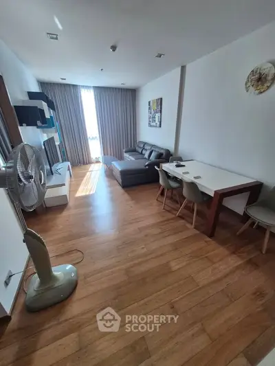 Spacious living room with modern furniture and wooden flooring, perfect for relaxation and entertainment.