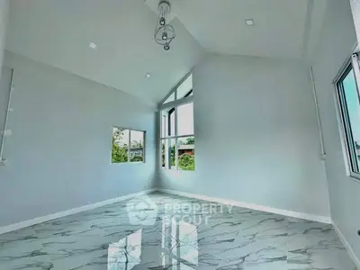 Spacious modern room with high ceilings and large windows offering natural light and scenic views.