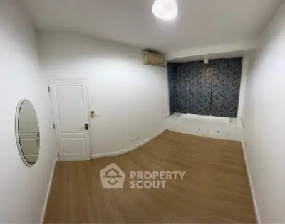 Spacious bedroom with wooden flooring and modern air conditioning unit.