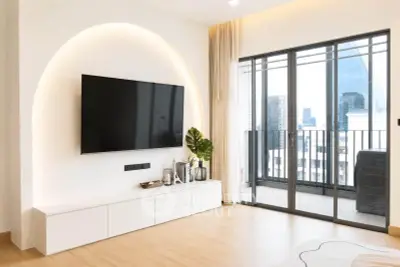 Modern living room with sleek TV setup and balcony view in urban apartment