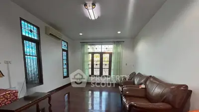 Spacious living room with leather sofa and large windows for natural light.
