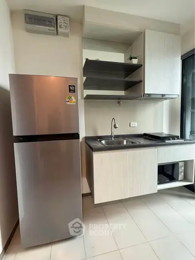 Modern kitchen with sleek appliances and open shelving in a contemporary apartment.