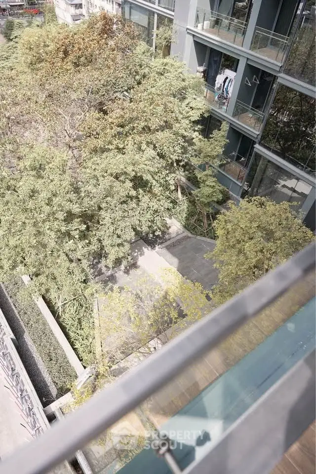 Modern building exterior with lush greenery and glass balconies, offering a serene urban living experience.