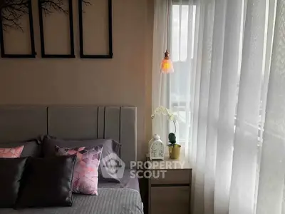 Cozy bedroom with stylish decor and natural light through sheer curtains.