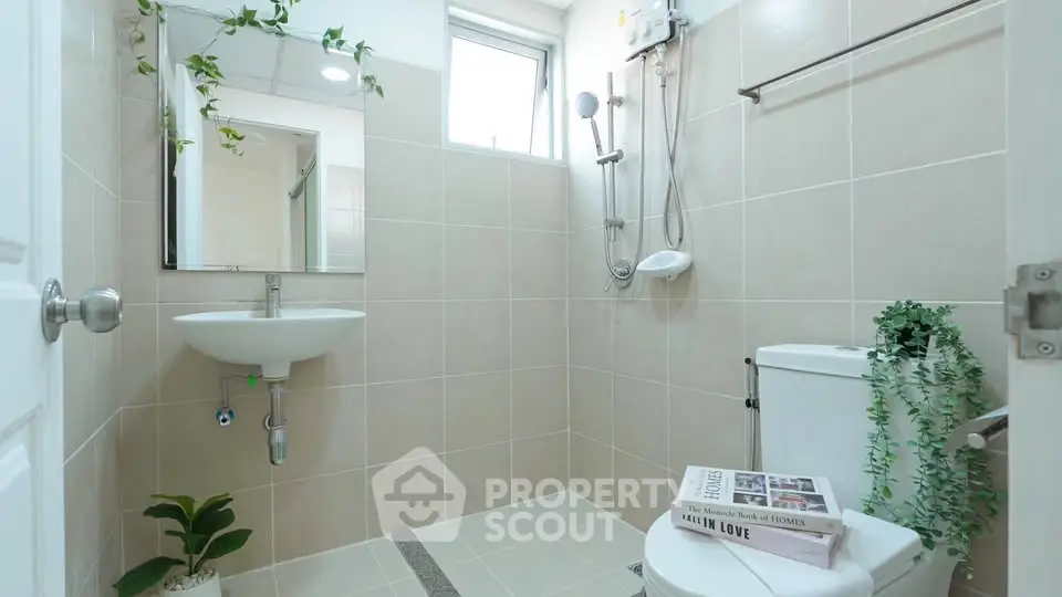 Modern bathroom with shower, sink, and toilet, featuring elegant tile design and greenery.