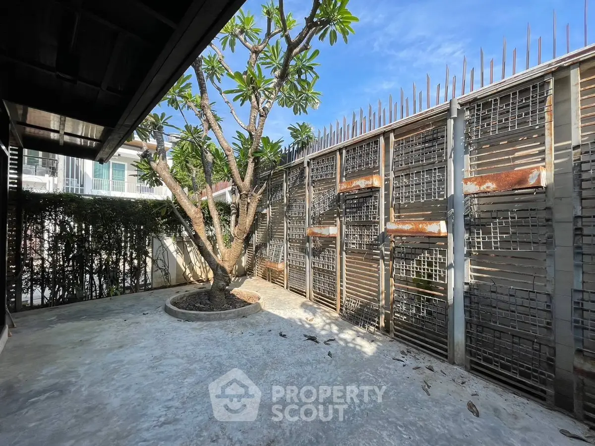 Charming outdoor patio with lush greenery and unique architectural fencing, perfect for relaxation and privacy.