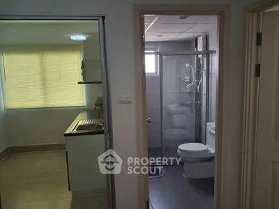 Compact apartment interior featuring a small kitchen and modern bathroom with shower.