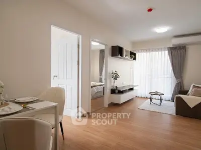 Modern living room with open layout and natural light, featuring stylish furniture and wooden flooring.