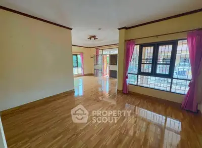 Spacious living room with polished wooden floors and large windows for natural light.