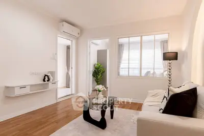 Modern living room with elegant decor and natural light, featuring a stylish glass coffee table and cozy seating.